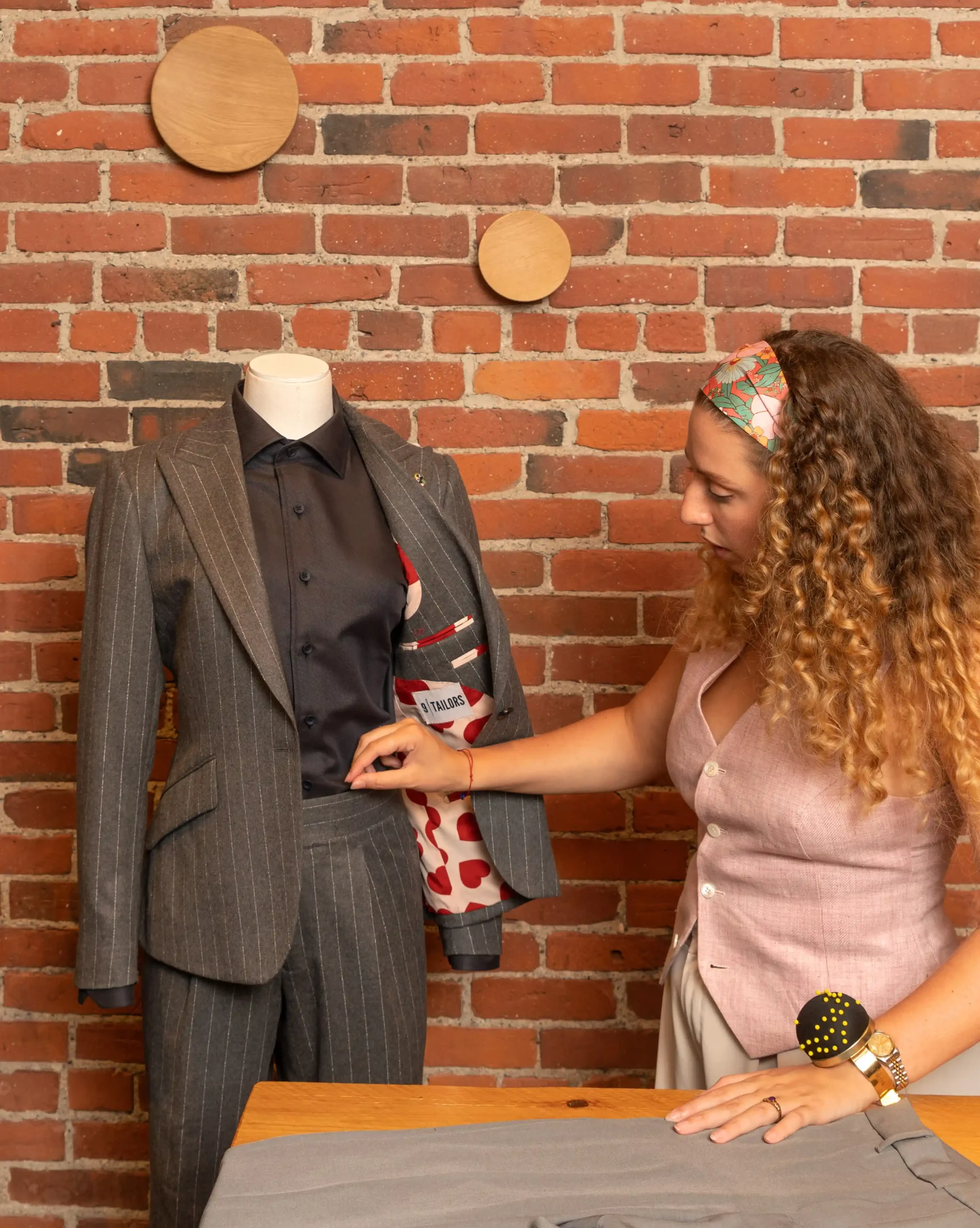A woman making tailoring adjustments to a suit on a mannequin