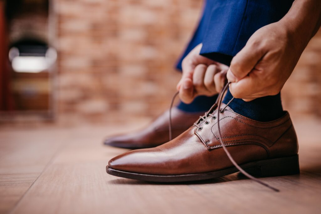 Hands tying leather shoes.